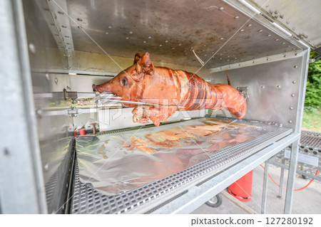 Barbecue with young pig grill Whole roasted piglet body turning on grill. Large barbecue in the process of cooking meat 127280192