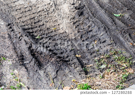 A detailed closeup image showcasing a tire track etched into the dirt 127280288