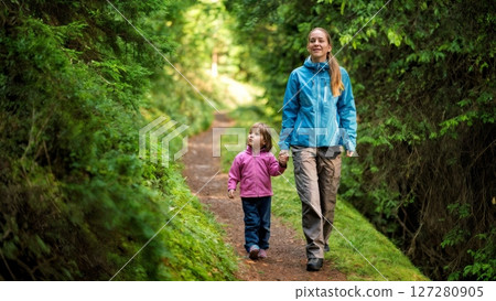 Mother and Daughter Hiking Through Forest Trail Holding Hands Mother and Daughter Hiking Through Forest Trail Holding Hands 127280905