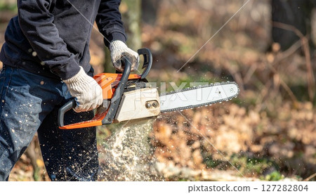 Man cutting down trees with a chainsaw 127282804