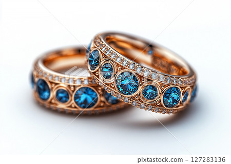 Luxurious pair of wedding rings with blue stones on a white background. Rococo-Renaissance style. 127283136