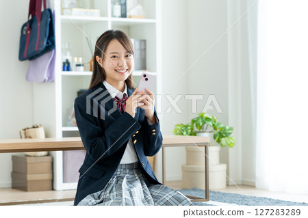 High school girl using a smartphone in her room 127283289