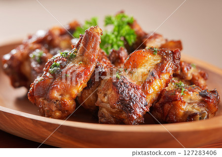 Close up of crispy glazed chicken wings on wooden plate. Hot and spicy chicken concept Close up of crispy glazed chicken wings on wooden plate. Hot and spicy chicken concept 127283406
