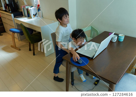 Two boys operating a computer in their home Two boys operating a computer in their home 127284616