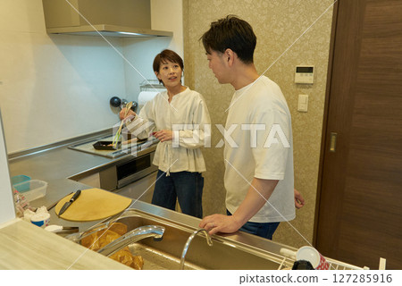 A couple doing housework together in the kitchen A couple doing housework together in the kitchen 127285916