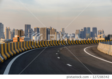 Curvy highway overpass with modern city background. Curvy highway overpass with modern city background. 127286342