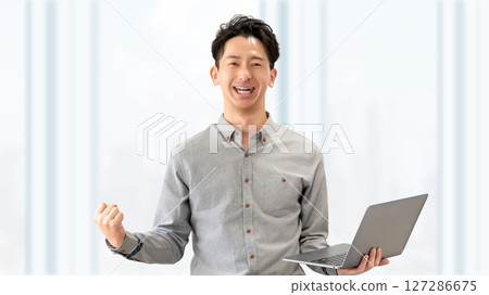 Smiling male businessman doing a fist pump Smiling male businessman doing a fist pump 127286675