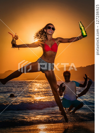 Woman having fun with a cocktail on the beach 127286925