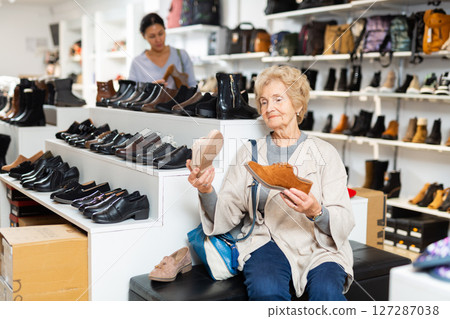 Old woman choosing new footwear in shoe store Old woman choosing new footwear in shoe store 127287038