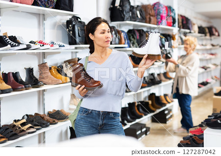 Focused asian woman chooses boots in the style of grinders 127287042