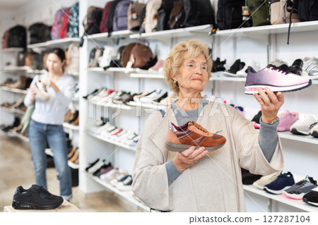Senior woman choosing running shoes in shoe store 127287104