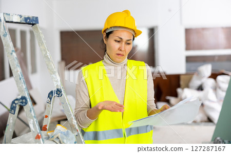 Woman worker checking documents during repair works indoors 127287167