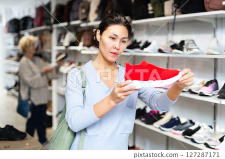 woman selecting running shoes in shoeshop 127287171