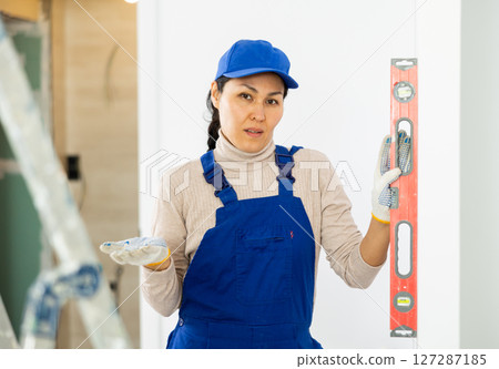 Female repairer setting level to wall 127287185