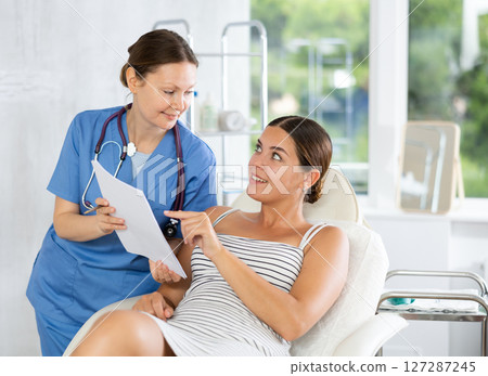 Adult female doctor shows contract to patient 127287245