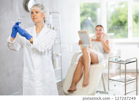 Doctor in disposable cap examine integrity of syringe with drug botulinum toxin before manipulations 127287249