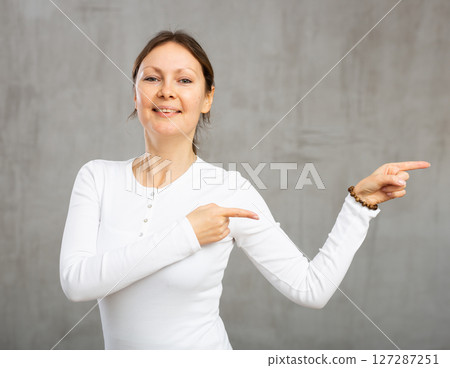 Smiling adult woman gesturing in studio 127287251