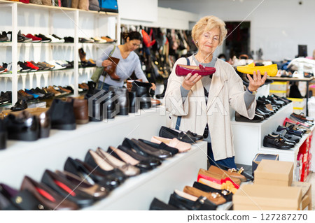 Elderly woman choosing moccasins in shoeshop Elderly woman choosing moccasins in shoeshop 127287270