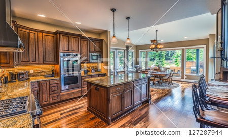 Modern Kitchen with Island and Large Windows Overlooking a Backyard 127287944