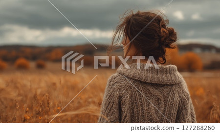 Woman in a Knit Sweater Contemplates an Autumn Field 127288260