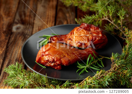 Smoked chicken drumsticks and juniper branches on a wooden table. 127289005