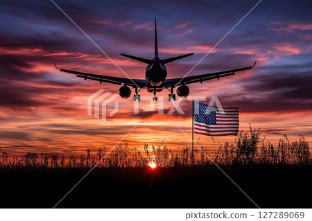 Silhouette of a passenger plane at sunrise or sunset over the US flag. 127289069