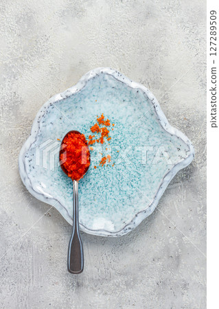 a spoon with orange flying fish caviar, Tobiko, on a light blue plate, caviar for rolls and sushi, close-up, a spoon with orange flying fish caviar, Tobiko, on a light blue plate, caviar for rolls and sushi, close-up, 127289509
