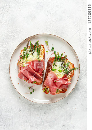 open sandwiches with asparagus and prosciutto, with cheese, breakfast, on a plate, 127289516