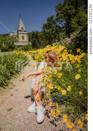A woman is sitting in a field of yellow flowers A woman is sitting in a field of yellow flowers 127291130