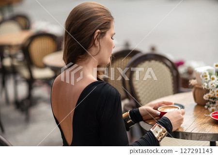 Woman Coffee Cafe: Back view of woman sipping latte at a cafe during daytime for relaxation. 127291143
