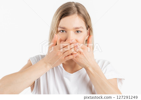 Portrait of young and beautiful woman with her hands covering mouth Portrait of young and beautiful woman with her hands covering mouth 127291249
