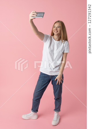 Young Woman Taking a Selfie on a Pink Background Young Woman Taking a Selfie on a Pink Background 127291342