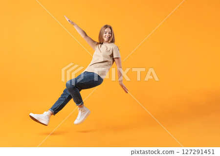 Joyful Leap Against Orange Backdrop Joyful Leap Against Orange Backdrop 127291451