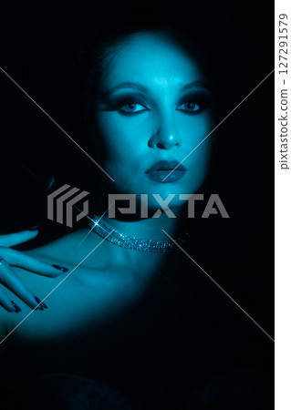 Woman portrait partly face covered with shadow and illuminated by blue light 127291579