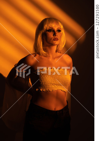 Beautiful woman with white wig illuminated by yellow light through blinds Beautiful woman with white wig illuminated by yellow light through blinds 127291580