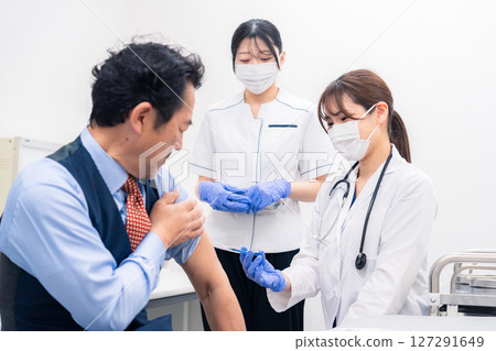A female medical worker administering a vaccine and taking blood 127291649