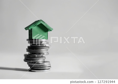 Stack of coins on top of a house 127291944