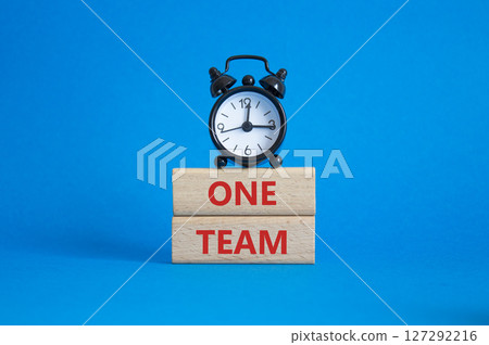 One Team symbol. Concept word One Team on wooden blocks. Beautiful blue background with alarm clock. Business and One Team concept. Copy space One Team symbol. Concept word One Team on wooden blocks. Beautiful blue background with alarm clock. Business and One Team concept. Copy space 127292216