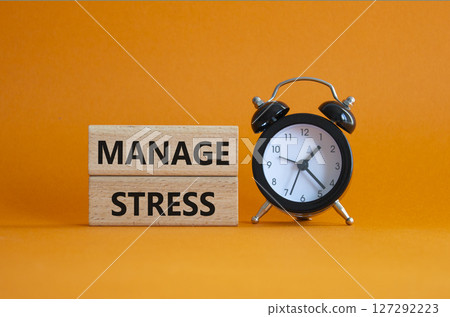 Manage stress symbol. Concept word Manage stress on wooden blocks. Beautiful orange background with alarm clock. Business and Manage stress concept. Copy space 127292223