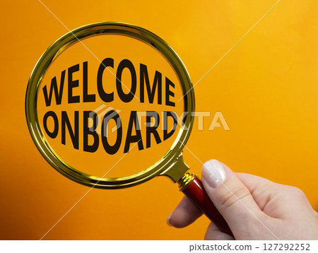 Welcome onboard symbol. Magnifying Glass with Concept word Welcome onboard. Businessman hand. Beautiful orange background. Business and Welcome onboard concept. Copy space 127292252