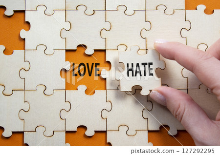 Love vs Hate symbol. Concept word Love vs Hate on wooden puzzle. Businessman hand. Beautiful orange background. Business and Love vs Hate concept. Copy space 127292295