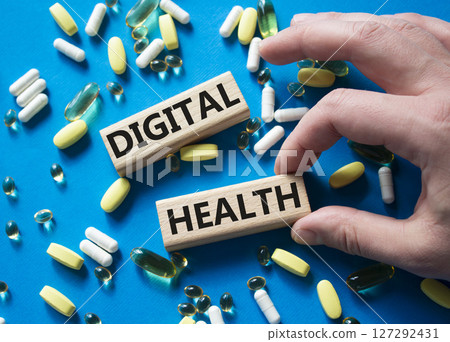 Digital Health symbol. Concept word Digital Health on wooden blocks. Doctor Hand. Beautiful blue background with pills. Medicine and Digital Health concept. Copy space 127292431