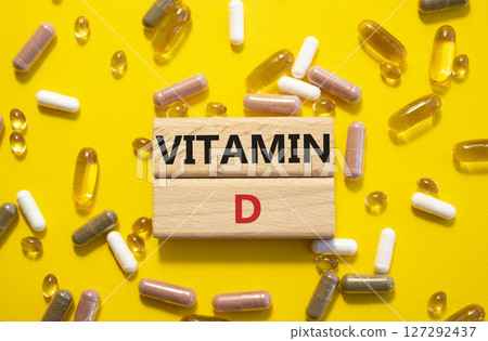 Vitamin D symbol. Concept word Vitamin D on wooden blocks. Beautiful yellow background with pills. Medicine and Vitamin D concept. Copy space Vitamin D symbol. Concept word Vitamin D on wooden blocks. Beautiful yellow background with pills. Medicine and Vitamin D concept. Copy space 127292437