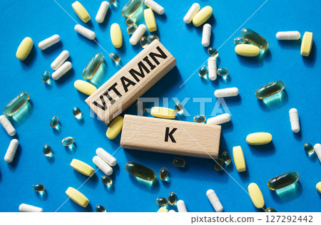 Vitamin K symbol. Concept word Vitamin K on wooden blocks. Beautiful blue background with pills. Medicine and Vitamin K concept. Copy space Vitamin K symbol. Concept word Vitamin K on wooden blocks. Beautiful blue background with pills. Medicine and Vitamin K concept. Copy space 127292442