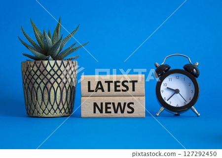 Latest News symbol. Concept words Latest News on wooden blocks. Beautiful blue background with alarm clock and succulent plant. Business and Latest News concept. Copy space. 127292450