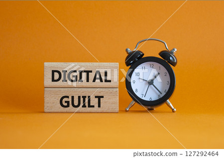 Digital Guilt symbol. Concept words Digital Guilt on wooden blocks. Beautiful orange background with alarm clock. Business and Digital Guilt concept. Copy space. Digital Guilt symbol. Concept words Digital Guilt on wooden blocks. Beautiful orange background with alarm clock. Business and Digital Guilt concept. Copy space. 127292464