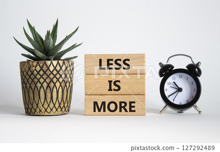 Less is More symbol. Concept words Less is More on wooden blocks. Beautiful white background with succulent plant and alarm clock. Business and Less is More concept. Copy space. 127292489