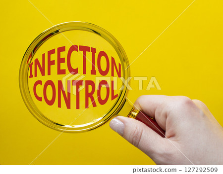 Infection Control symbol. Magnifying Glass with Concept word Infection Control. Businessman hand. Beautiful yellow background. Business and Infection Control concept. Copy space 127292509