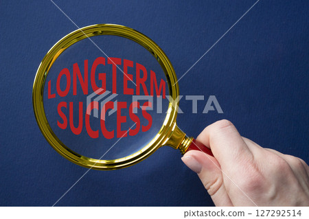Longterm success symbol. Magnifying Glass with Concept word Longterm success. Businessman hand. Beautiful deep blue background. Business and Longterm success concept. Copy space 127292514