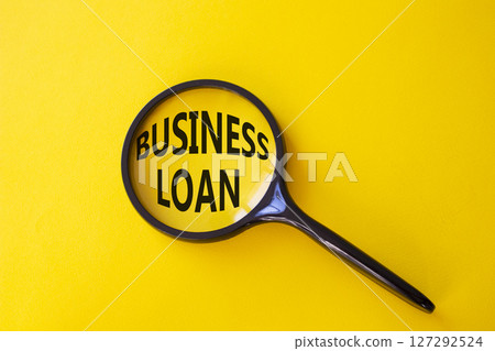 Business loan symbol. Magnifying glass with words Business loan. Beautiful yellow background. Business and Business loan concept. Copy space. 127292524